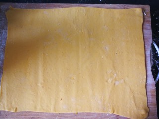 千层手撕南瓜馒头,案板上撒上些手粉,将面团擀成规则点的长方形薄片。