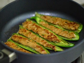 青椒酿肉,锅里放适量油,先将肉朝下,煎至金黄后翻转煎另外一面(翻转的时候小心点,肉容易掉出来)